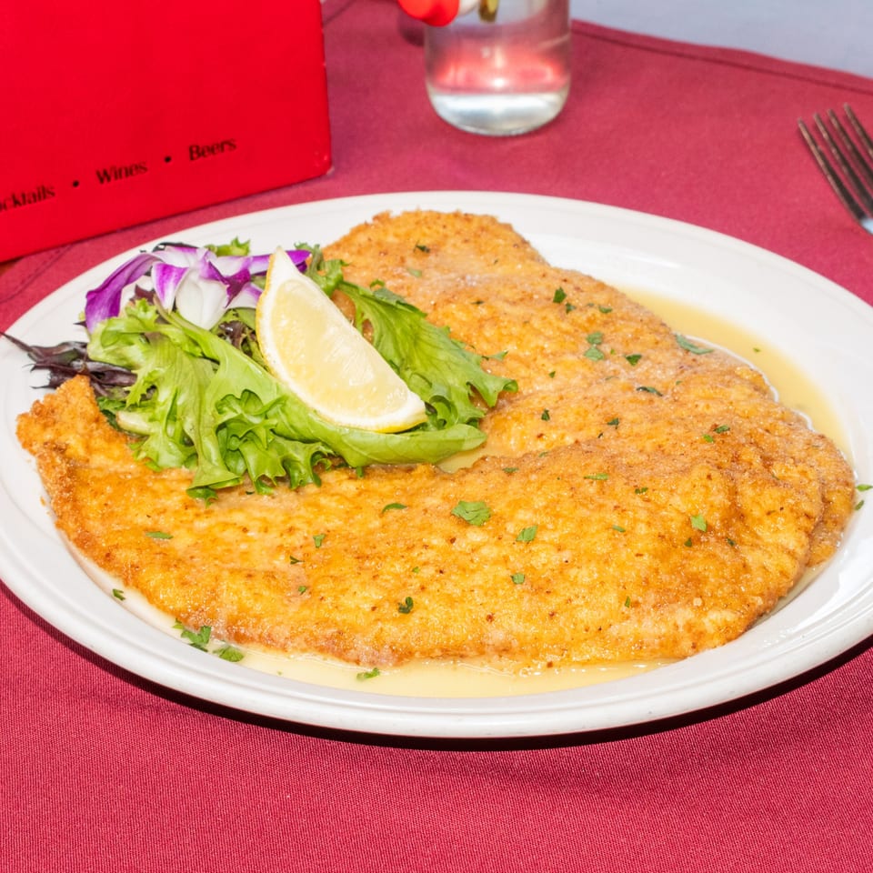 Sorrento Restaurant's chicken Milanese, breaded and fried, with a lemon wedge and side salad.