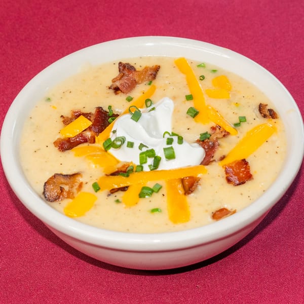 Creamy potato soup topped with shredded cheddar, bacon bits, sour cream, and chives.