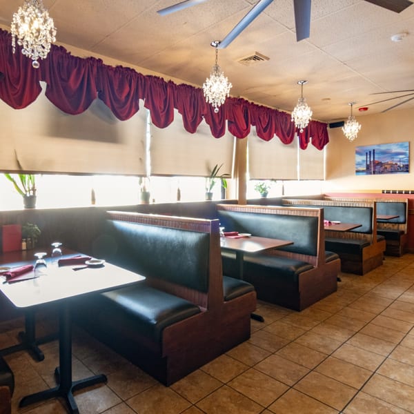 Sorrento Restaurant's dining room with booth seating, set tables, chandeliers, and red valances.