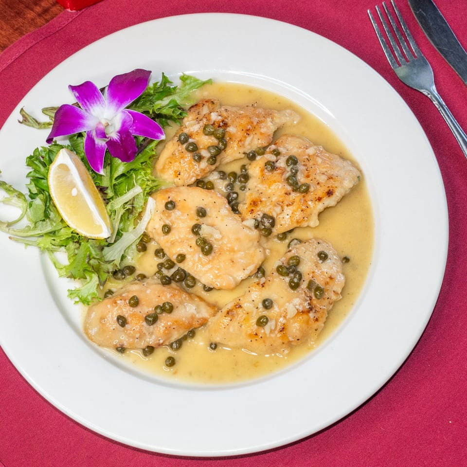 Sorrento Restaurant's chicken piccata with capers, lemon, and a purple orchid garnish.