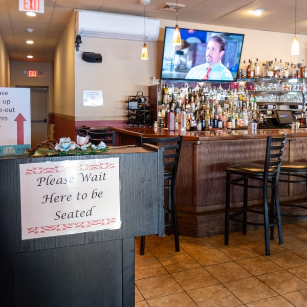 A "Please Wait Here to be Seated" sign at the entrance of Sorrento Restaurant's bar area.