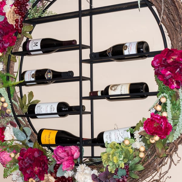 A decorative wine rack with several bottles of Italian wine, adorned with flowers and grapes.