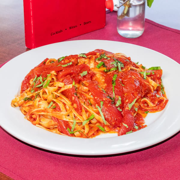 Fettuccine pasta with rich red tomato sauce and fresh basil on a white plate at Sorrento Restaurant.