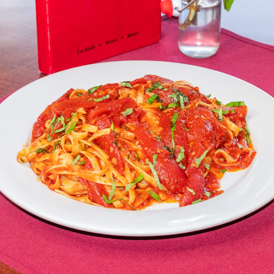 Fettuccine pasta with rich red tomato sauce and fresh basil on a white plate at Sorrento Restaurant.